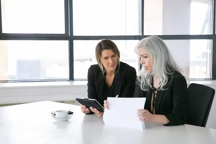 Two colleagues reviewing a report by a window